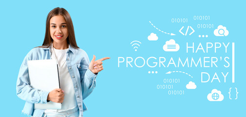 Young woman with laptop and text HAPPY PROGRAMMER'S DAY on light blue background