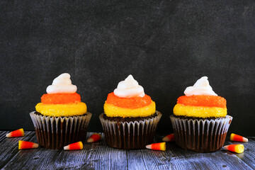Poster - Halloween candy corn chocolate cupcakes in a row against a dark background