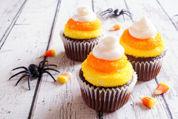 Poster - Halloween candy corn chocolate cupcakes over a rustic white wood table background