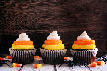 Poster - Halloween candy corn chocolate cupcakes against a dark wood background.