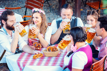 Wall Mural - Group of women and men in Bavarian Beer garden drinking from glasses