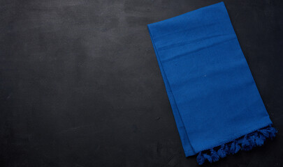 Wall Mural - Blue linen kitchen towel on a black background, top view. Copy space