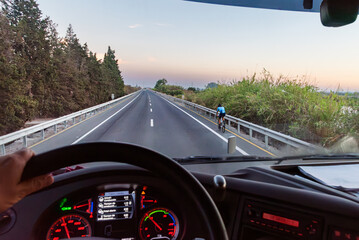 View from the driver's position of a truck of the highway with a cyclist riding on the shoulder.