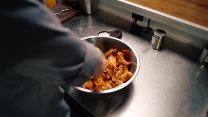 Wall Mural - professional restaurant kitchen chef stirs chicken wings with spices in a bowl asian dish close-up