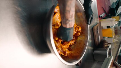 Wall Mural - professional restaurant kitchen chef stirs chicken wings with spices in a bowl asian dish close-up vertical video