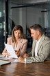 © insta_photos - Mature business woman manager holding legal documents consulting client at office meeting, two professional executives experts discussing financial accounting papers working together. Vertical.