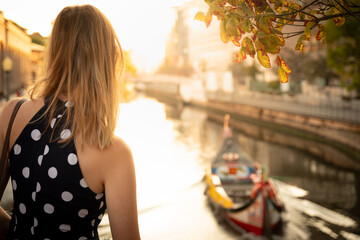 40 years old blonde make tourism in front of sea canal with Moliceiro boat at golden sunset Aveiro, Portugal 