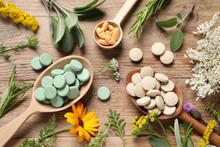 Different Pills, Herbs And Flowers On Wooden Table, Flat Lay. Dietary Supplements