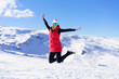 © javiindy - Carefree young woman jumping with raised arms on snow terrain