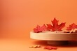 Autumn themed setup with wooden podium red leaves and orange backdrop