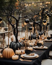 A Black And Gold Halloween Dinner Table Setting With Pumpkins, Candles, Trees And Other Decorations In The Background
