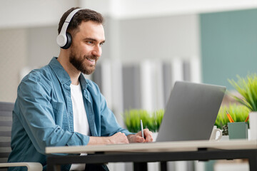 Aufkleber - Online Education. Smiling Man Wearing Wireless Headphones Using Laptiop And Taking Notes
