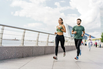 People in sportswear are runners, physical education and sports. Running man and woman train.  Using a smartwatch and a fitness app.  Team exercises of a young couple.