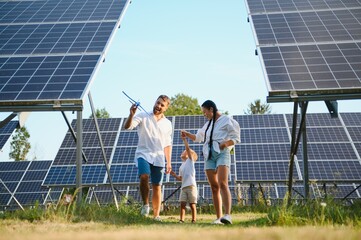 The concept of green energy. Happy family walking and having fun in solar panel field. Green energy.