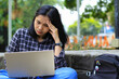 © M Alfan Setyawan - exhausted and stressed asian woman student working using laptop and study with text books in outdoors