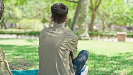 Sticker - Young hispanic man tourist sitting on floor backwards at park