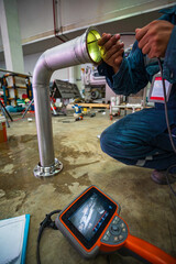 Wall Mural - A man starts using a weld pipe stainless inspection camera. The light monitor shows images from the camera head that the inspector