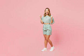 Wall Mural - Full body young smiling happy woman she wear casual clothes look camera doing winner gesture celebrate clenching fists say yes isolated on plain pastel light pink background studio. Lifestyle concept.