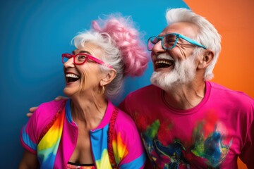 Wall Mural - Happy old couple in colorful clothes in front of a colorful background wall.