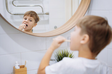 Wall Mural - cute 5 years old boy brushing teeth with bamboo tooth brush in bathroom. Image with selective focus