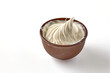 A portion of whipped cream or sour cream twisted into a spiral. Butter in clay bowl isolated on white background