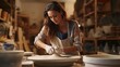 © Fred - Close up Portrait of a woman at a ceramics workshop glazing a freshly shaped pottery piece