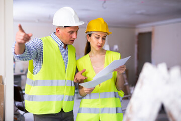 Wall Mural - Woman architect and man engineer having conversation about work plan in apartment. Pointing with finger, showing with hand gesture.