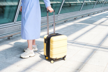  Young woman with yellow suitcase near the airport, travel concept.