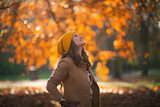Fototapeta  - smiling elegant woman in brown coat and yellow hat