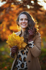 Wall Mural - smiling trendy 40 years old woman in brown coat and yellow hat