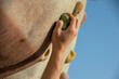 Close-up of the right hand of a young Caucasian man grabbing the handle on a climbing wall.
