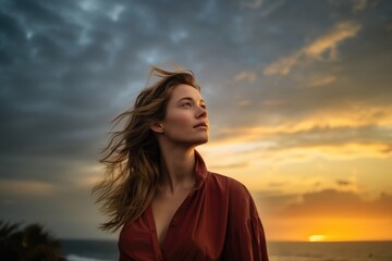 Wall Mural - Young woman looking up at the sky at sunset