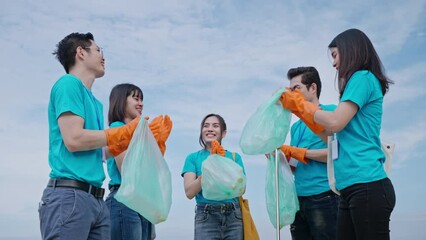 Wall Mural - volunteering,charity,cleaning,people and ecology concept.group of happy volunteers with garbage bags and join hand together after cleaning area on beach.environment,Ecology,volunteer charity work