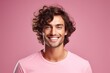 Portrait of a young man smiling at the camera, showing his radiant and youthful skin on pink background