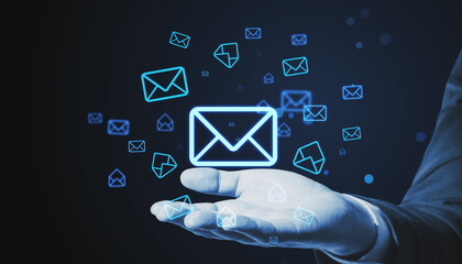 Poster - Close up of businessman hand holding glowing email letter icons on dark blue background. Communication and business message concept.