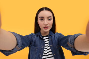 Canvas Print - Young woman taking selfie on yellow background