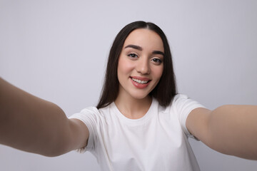 Sticker - Smiling young woman taking selfie on white background