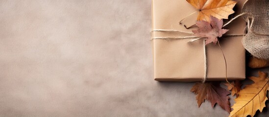 Poster - Autumn arrangement featuring dried leaves a wrapped gift placed in a corner on rustic linen background Top view copy space