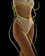 © Lustre Art Group  - Cropped slim female body in khaki lingerie with drawn yellow silhouette around body posing against black background. body positivity