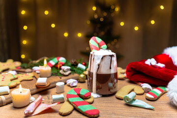 Gingerbread candy cane in a cup of hot chocolate with whipped cream, Christmas interior. Close up