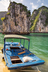 Wall Mural - A colourful fishing boat on the beach in front of large mountains in the sea at Ha Long Bay in Vietnam