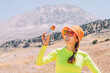 © EdNurg - Pretty young woman biting on a energy sportive gel drink after a good hike in high mountains