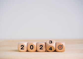 Wall Mural - 2024 happy new year with the goal and successful banner concepts. Flipping the 2023 to 2024 year numbers calendar with goal target icon on wooden cube blocks on wood table on white background.