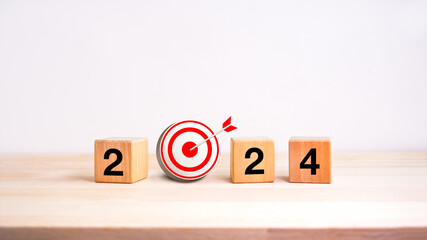 Poster - 2024 business goal and success concept banner. Text, year number on wooden cube block with 3d target dart icon on wood table and white background. Welcome, Merry Christmas, and Happy New Year in 2024.