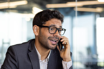 Wall Mural - Dissatisfied and upset man talking on phone close up, businessman young in business clothes at workplace inside office.