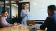© Jacob Lund - Group of professionals having a discussion in a meeting. Business woman stands in a boardroom doing a presentation