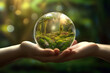 Hand holding a glass globe with green moss in the forest. Ecology concept.