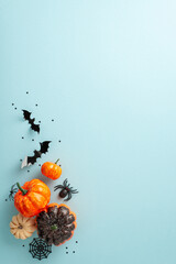 Wall Mural - Join the celebration of spooky Halloween night. Top-view vertical shot presenting pumpkins, spiders and Halloween decorations on a blue isolated background. Great for advertising or text integration