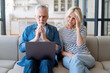 © brizmaker - Upset mature couple looking at computer and getting shocking bad news