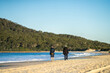couple walking on the beach, women in coats and beanies walk down a winter beach in hobart tasmania, australia.